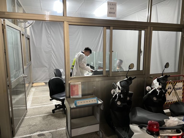 圖片說明：警員穿著全套防護裝備於戶外隔離偵詢室偵訊犯嫌。(記者謝榮浤翻攝)