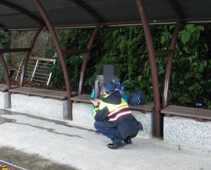 圖片說明：見男童獨坐校門口，基隆市警察局第二分局八斗子分駐所警員羅國倫上前關切。(記者宋紹誠翻攝)